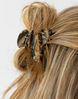 France Luxe small French claw hair clip for women pictured holding straight, blonde hair in a half up hairstyle.