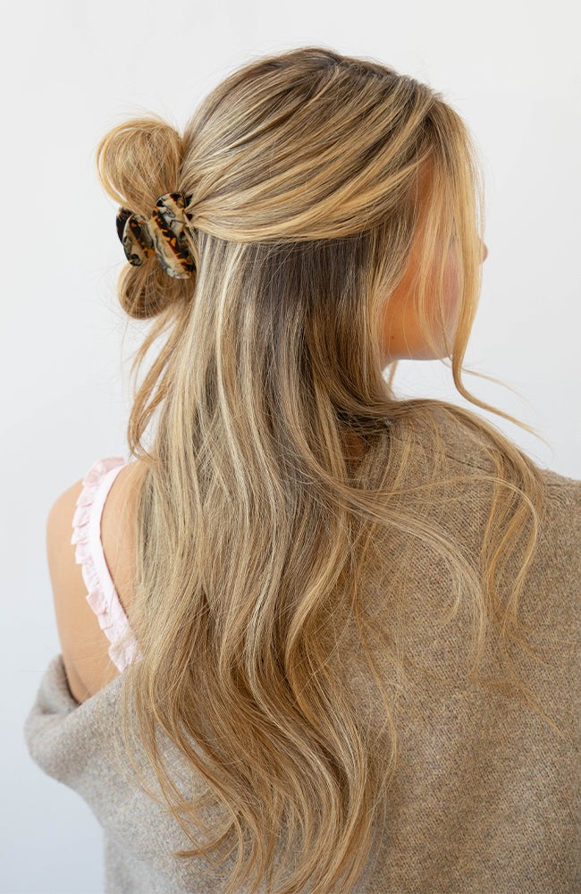France Luxe small, brown claw hair clip for women pictured holding straight, blonde hair in a half up hairstyle.