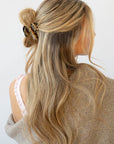 France Luxe small, brown claw hair clip for women pictured holding straight, blonde hair in a half up hairstyle.