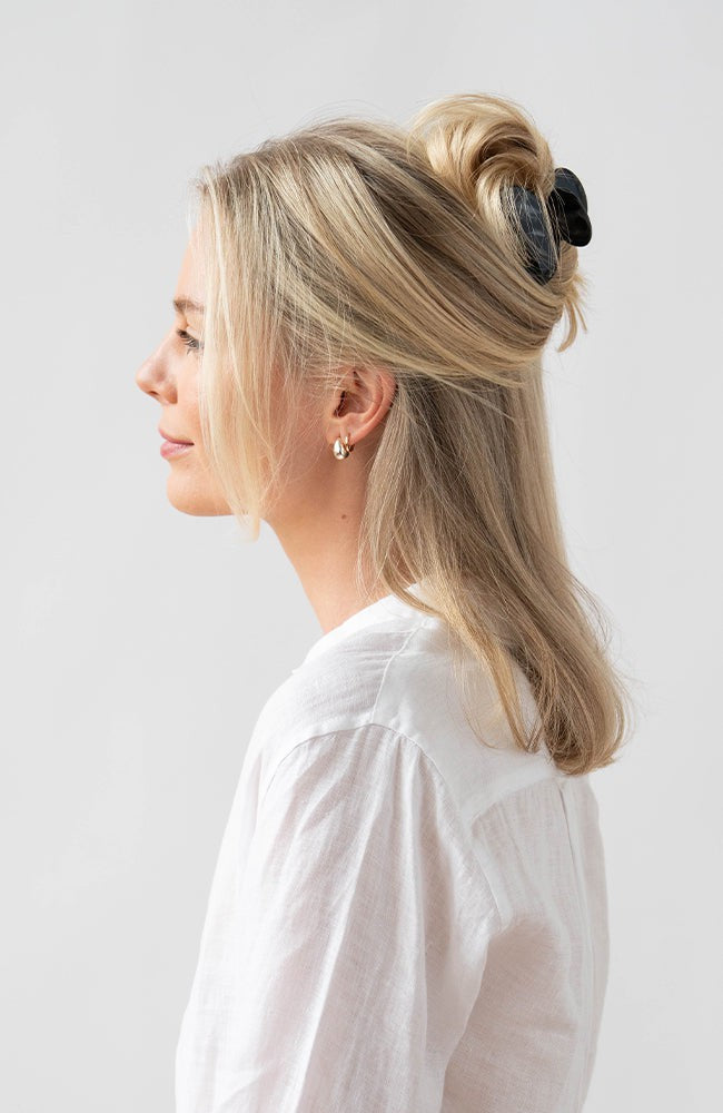 France Luxe small French claw hair clip for women pictured holding straight, blonde hair in a half up hairstyle.