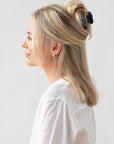 France Luxe small French claw hair clip for women pictured holding straight, blonde hair in a half up hairstyle.