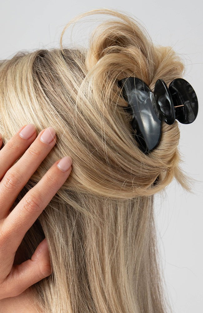 France Luxe small French claw hair clip for women pictured holding straight, blonde hair in a half up hairstyle.