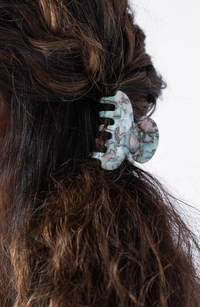France Luxe small French claw hair clip for women pictured holding curly, brown hair in a half up hairstyle.