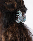 France Luxe small French claw hair clip for women pictured holding curly, brown hair in a half up hairstyle.