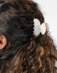 France Luxe small French claw hair clip for women pictured holding curly, brown hair in a half up hairstyle.