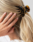 France Luxe small French claw hair clip for women pictured holding straight, blonde hair in a half up hairstyle.