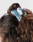 France Luxe medium French claw hair clip for women pictured holding curly, brown hair in a half up twist hairstyle.