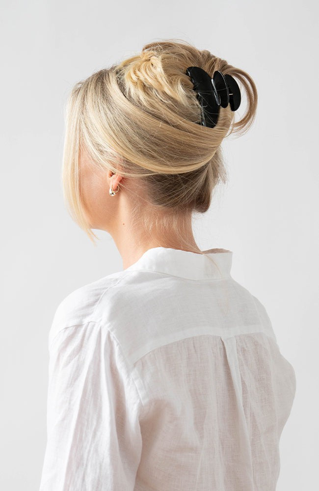 Woman with straight, blonde hair styled in an updo with a France Luxe medium claw hair clip, classic black.