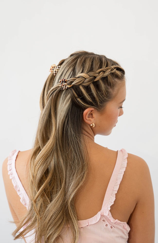 France Luxe mini French claw hair clip for women pictured holding straight, blonde hair in a braided hairstyle.