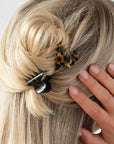 France Luxe mini French claw hair clip for women pictured holding straight, blonde hair in a half up bun hairstyle.
