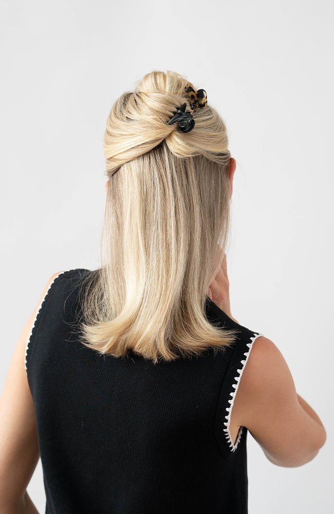 France Luxe mini, black claw hair clip for women pictured holding straight, blonde hair in a half up hairstyle.