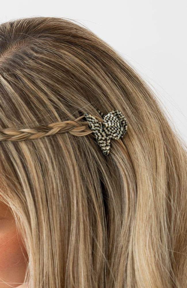 France Luxe mini French claw hair clip for women pictured holding straight, blonde hair in a braided hairstyle.