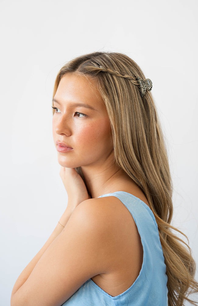France Luxe mini French claw hair clip for women pictured holding straight, blonde hair in a braided hairstyle.