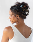 Mini Claw Hair Clip by France Luxe pictured holding curly, brown hair back in a loose bun with multiple different colored hair clips.