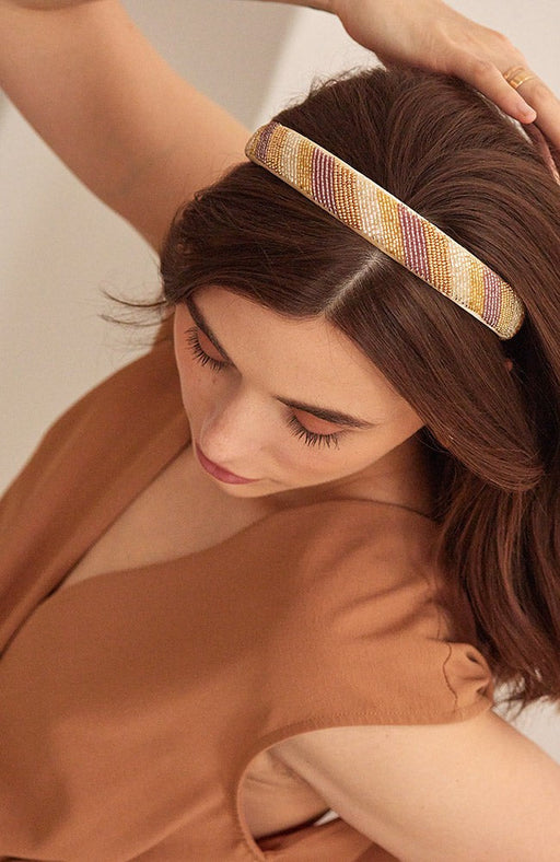 Beaded headband features pink, gold and white beads. Pictured in straight brown hair.