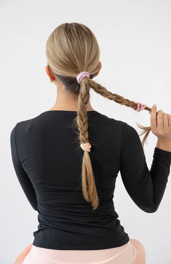 Woman using pink L. Erickson hair ties for fine hair. Strong and gentle. Damage free, crease free.