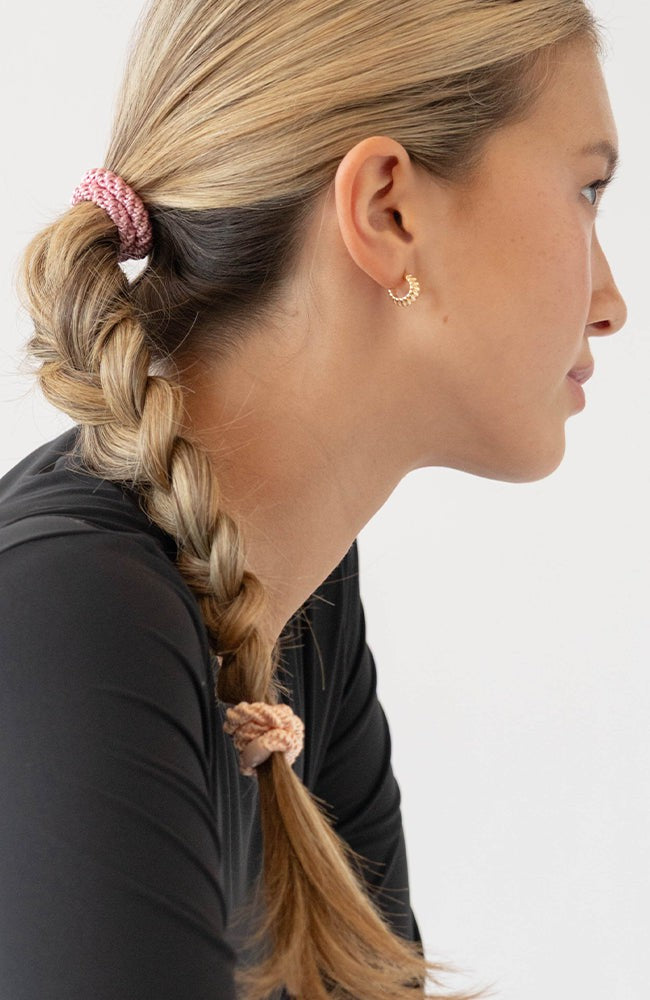 Pink hair ties styling a cute braided ponytail, straight, light brown hair. By L. Erickson.