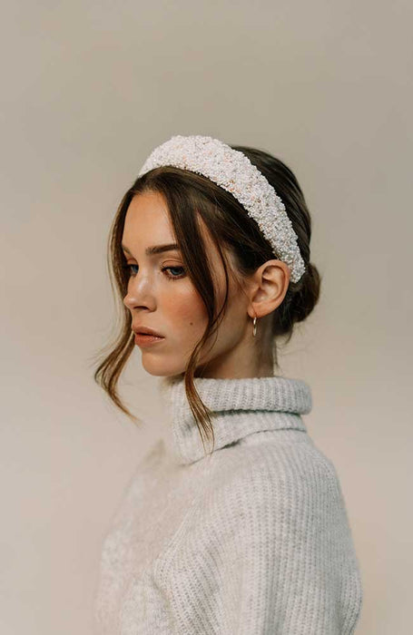 White beaded headband by L. Erickson, pictured on a women with brown hair styled in an updo with long bangs