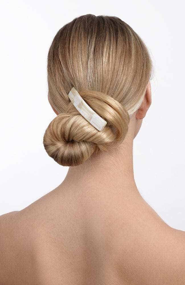 Woman with straight, blonde hair styled in a low bun with a France Luxe medium, White barrette.