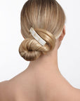 Woman with straight, blonde hair styled in a low bun with a France Luxe medium, White barrette.