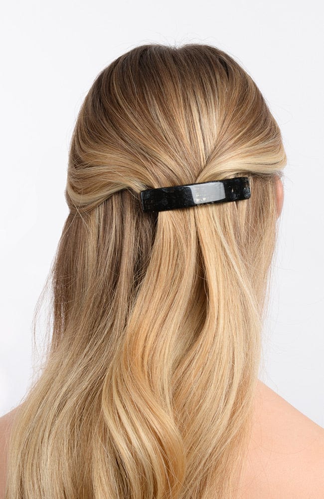 France Luxe medium, black barrette for women pictured holding straight, blonde hair in a half up hairstyle.