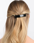 France Luxe medium, black barrette for women pictured holding straight, blonde hair in a half up hairstyle.
