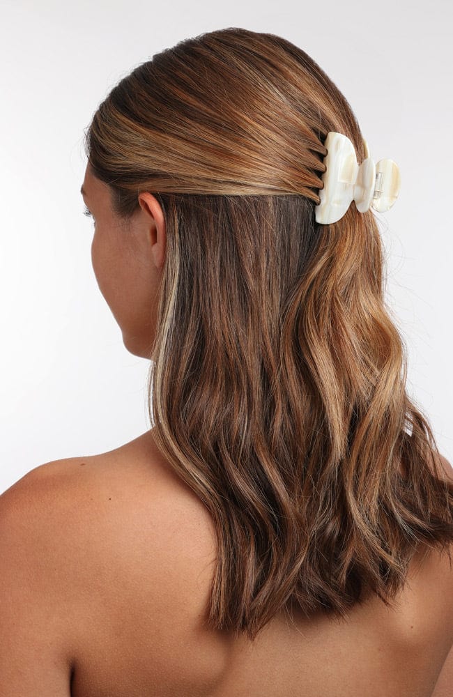 France Luxe small French claw hair clip for women pictured holding straight, brown hair in a half up hairstyle.